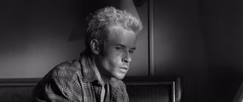 Movie still from “Memento” (2000), directed by Christopher Nolan – Black and white photograph of a young man with blonde spiky hair; Close Up shot, High angle