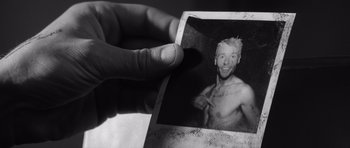 Movie still from “Memento” (2000), directed by Christopher Nolan – A person holding a photo of a shirtless man; Extreme Close Up shot, High angle