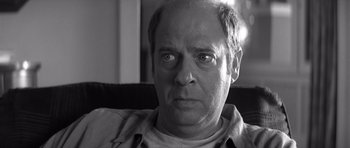 Movie still from “Memento” (2000), directed by Christopher Nolan – Black and white photograph of an older man looking at the camera; Close Up shot, Low angle