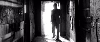 Movie still from “Memento” (2000), directed by Christopher Nolan – A man in a suit walking through a doorway; Wide shot, Low angle