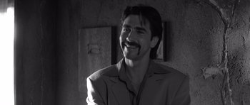 Movie still from “Memento” (2000), directed by Christopher Nolan – Black and white photograph of a man smiling; Close Up shot, Over the shoulder angle