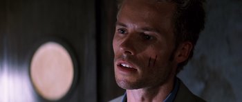 Movie still from “Memento” (2000), directed by Christopher Nolan – A person with a scar on his face; Close Up shot, Low angle