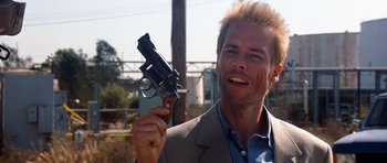Movie still from “Memento” (2000), directed by Christopher Nolan – A man holding up a gun with blood on his face; Close Up shot, Low angle