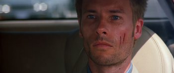 Movie still from “Memento” (2000), directed by Christopher Nolan – A person in a car looking at the camera; Close Up shot, High angle