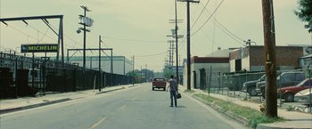 Movie still from “Million Dollar Baby” (2004), directed by Clint Eastwood – A man standing on the side of a road holding a bag; Extreme Wide shot, Over the shoulder angle
