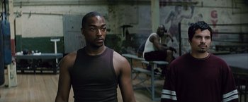 Movie still from “Million Dollar Baby” (2004), directed by Clint Eastwood – A man standing in a room with other men; Medium shot, Over the shoulder angle