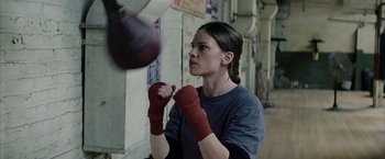 Movie still from “Million Dollar Baby” (2004), directed by Clint Eastwood – A young woman is practicing boxing in a gym; Medium shot, Low angle
