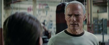 Movie still from “Million Dollar Baby” (2004), directed by Clint Eastwood – An older man in a gray t - shirt is talking to a younger man; Close Up shot, Over the shoulder angle