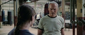 Movie still from “Million Dollar Baby” (2004), directed by Clint Eastwood – An older man and a young woman in front of a punching bag in a gym; Medium shot, Over the shoulder angle