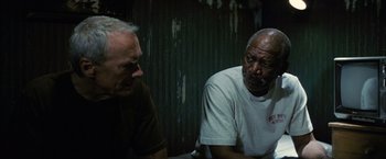 Movie still from “Million Dollar Baby” (2004), directed by Clint Eastwood – Two older men sitting next to each other in front of a wall; Medium shot, Low angle