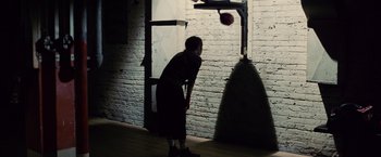 Movie still from “Million Dollar Baby” (2004), directed by Clint Eastwood – A man is playing basketball in the dark; Wide shot, High angle
