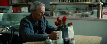 Movie still from “Million Dollar Baby” (2004), directed by Clint Eastwood – An older man sitting at a table with a vase of roses; Close Up shot, Over the shoulder angle