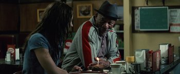 Movie still from “Million Dollar Baby” (2004), directed by Clint Eastwood – An older man sitting at a table in front of a lit candle; Medium shot, Over the shoulder angle