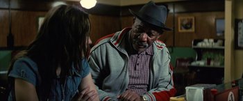 Movie still from “Million Dollar Baby” (2004), directed by Clint Eastwood – An older man wearing a hat is talking to a young woman; Medium shot, Over the shoulder angle