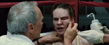 Movie still from “Million Dollar Baby” (2004), directed by Clint Eastwood – An older man and a young woman with bruises on their face; Close Up shot, High angle