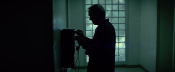 Movie still from “Million Dollar Baby” (2004), directed by Clint Eastwood – A man standing in front of a wall mounted phone; Medium shot, Low angle