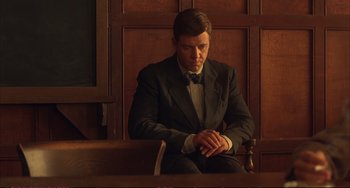 Movie still from “A Beautiful Mind” (2001), directed by Ron Howard – A man in a suit sitting in front of a judge's bench; Medium shot, Low angle