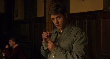 Movie still from “A Beautiful Mind” (2001), directed by Ron Howard – A man in a green shirt holding a red object in his hand; Close Up shot, High angle