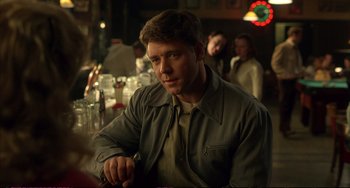 Movie still from “A Beautiful Mind” (2001), directed by Ron Howard – A man sitting at a table in front of glasses; Medium shot, Over the shoulder angle