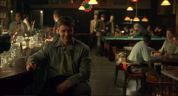 Movie still from “A Beautiful Mind” (2001), directed by Ron Howard – A man sitting at a table in front of a pool table; Medium shot, Over the shoulder angle