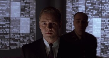 Movie still from “A Beautiful Mind” (2001), directed by Ron Howard – A man wearing a suit and tie standing next to another man in a suit; Medium shot, Low angle