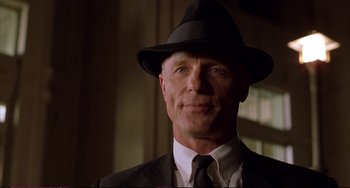 Movie still from “A Beautiful Mind” (2001), directed by Ron Howard – A person wearing a suit and a hat; Close Up shot, Low angle