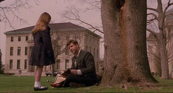 Movie still from “A Beautiful Mind” (2001), directed by Ron Howard – A man sitting on the ground next to a tree; Medium shot, Over the shoulder angle