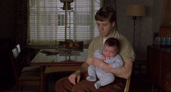 Movie still from “A Beautiful Mind” (2001), directed by Ron Howard – A man holding a crying baby in his arms; Medium shot, Over the shoulder angle