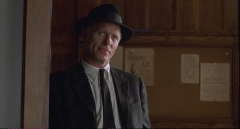 Movie still from “A Beautiful Mind” (2001), directed by Ron Howard – A man in a suit and hat standing in a room; Close Up shot, Over the shoulder angle