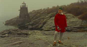 Movie still from “Moonrise Kingdom” (2012), directed by Wes Anderson – An older man in a red coat standing on a rocky hill; Wide shot, Low angle