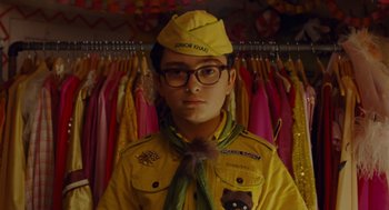 Movie still from “Moonrise Kingdom” (2012), directed by Wes Anderson – A man in a yellow uniform and a cat hat; Medium shot, Over the shoulder angle
