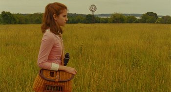 Movie still from “Moonrise Kingdom” (2012), directed by Wes Anderson – A woman in a field holding a basket and a camera; Medium shot, Over the shoulder angle