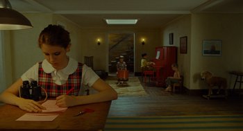 Movie still from “Moonrise Kingdom” (2012), directed by Wes Anderson – A woman sitting at a table writing on a piece of paper; Wide shot, High angle