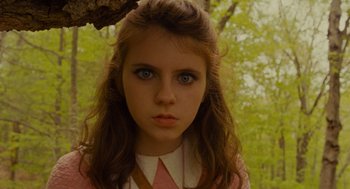 Movie still from “Moonrise Kingdom” (2012), directed by Wes Anderson – A young girl with blue eyes is standing in front of a tree; Close Up shot, Low angle