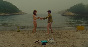 Movie still from “Moonrise Kingdom” (2012), directed by Wes Anderson – Two young women on the beach shaking hands in front of the ocean; Wide shot, High angle