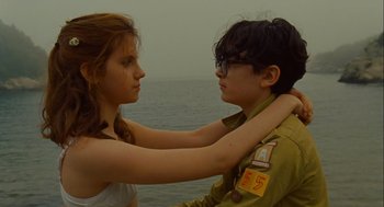 Movie still from “Moonrise Kingdom” (2012), directed by Wes Anderson – A young man and a young woman standing next to a body of water; Medium shot, Low angle