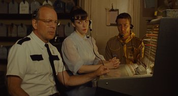 Movie still from “Moonrise Kingdom” (2012), directed by Wes Anderson – Three people sitting at a table with a laptop; Medium shot, Over the shoulder angle