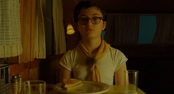 Movie still from “Moonrise Kingdom” (2012), directed by Wes Anderson – A woman sitting at a table in front of a plate of food; Medium shot, Low angle
