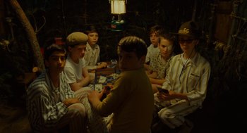Movie still from “Moonrise Kingdom” (2012), directed by Wes Anderson – A group of young men sitting around a table; Medium shot, High angle