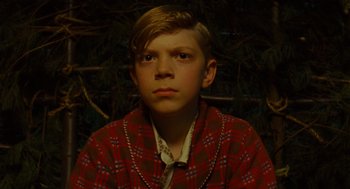 Movie still from “Moonrise Kingdom” (2012), directed by Wes Anderson – A young boy wearing a plaid shirt and a tie; Close Up shot, High angle