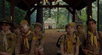 Movie still from “Moonrise Kingdom” (2012), directed by Wes Anderson – A group of young men sitting next to each other in front of a building; Medium shot, Low angle