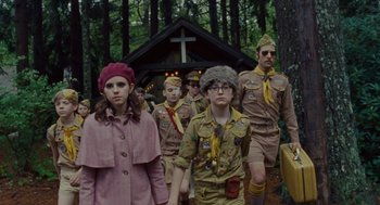 Movie still from “Moonrise Kingdom” (2012), directed by Wes Anderson – A group of young people dressed like scouts walking through the woods; Medium shot, Low angle