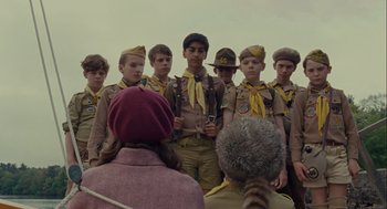 Movie still from “Moonrise Kingdom” (2012), directed by Wes Anderson – A group of boy scouts standing in front of an older woman; Medium shot, Over the shoulder angle