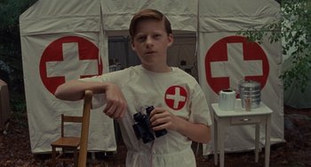 Movie still from “Moonrise Kingdom” (2012), directed by Wes Anderson – A young boy holding a pair of video game controllers; Medium shot, Low angle