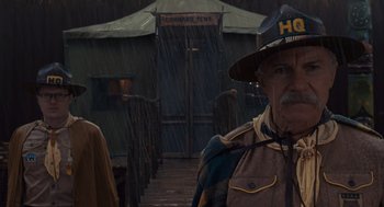 Movie still from “Moonrise Kingdom” (2012), directed by Wes Anderson – An old man in a hat standing in the rain; Medium shot, Low angle