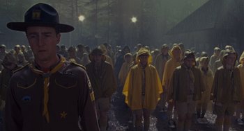Movie still from “Moonrise Kingdom” (2012), directed by Wes Anderson – A group of people in raincoats are standing in the rain; Wide shot, Low angle