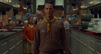 Movie still from “Moonrise Kingdom” (2012), directed by Wes Anderson – A man in a uniform standing in front of a crowd of onlookers; Medium shot, Low angle