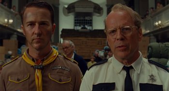 Movie still from “Moonrise Kingdom” (2012), directed by Wes Anderson – Two men standing next to each other in front of a crowd of onlookers; Close Up shot, Low angle