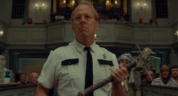 Movie still from “Moonrise Kingdom” (2012), directed by Wes Anderson – A man holding a baseball bat while standing in front of a crowd; Close Up shot, Low angle