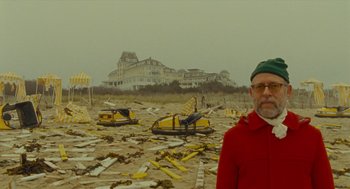 Movie still from “Moonrise Kingdom” (2012), directed by Wes Anderson – A man standing in front of a pile of debris on the beach; Medium shot, Over the shoulder angle